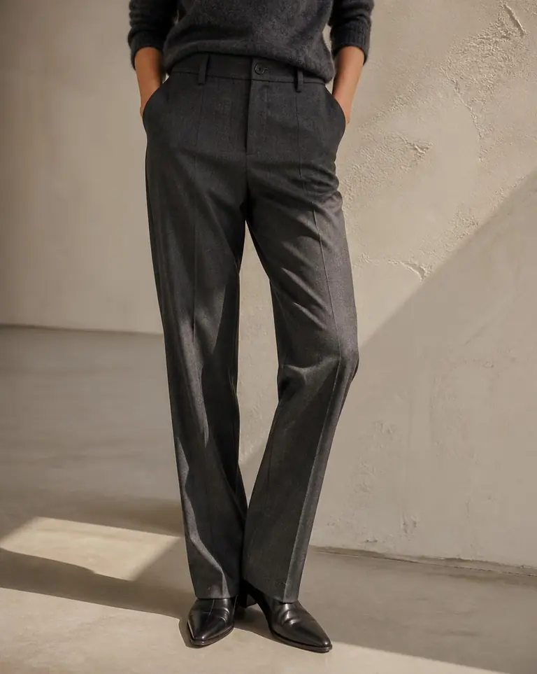 Model wearing charcoal straight-leg wool flannel trousers in hard daylight.